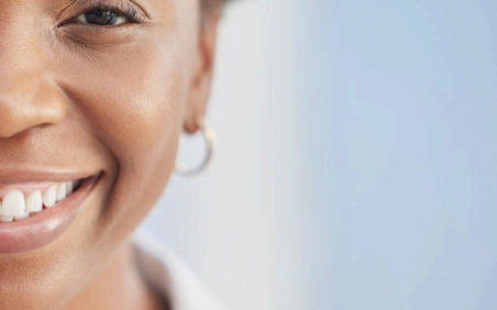 Persona sonriente con pendiente de aro sobre un fondo azul claro