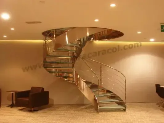 Una escalera de caracol con barandilla de acero inoxidable y escalones de cristal.