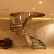 Una escalera de caracol con barandilla de acero inoxidable y escalones de cristal.