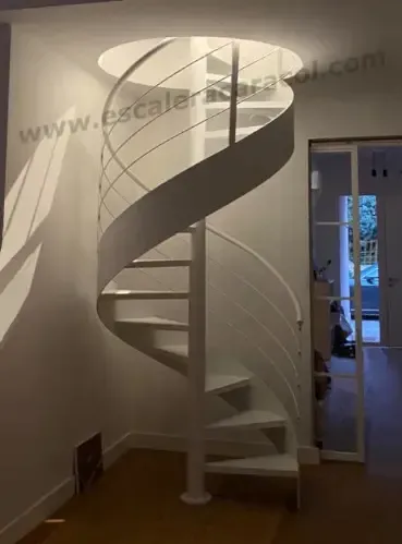Una escalera de caracol blanca en un pasillo con la página web www.escaleriurasol.com