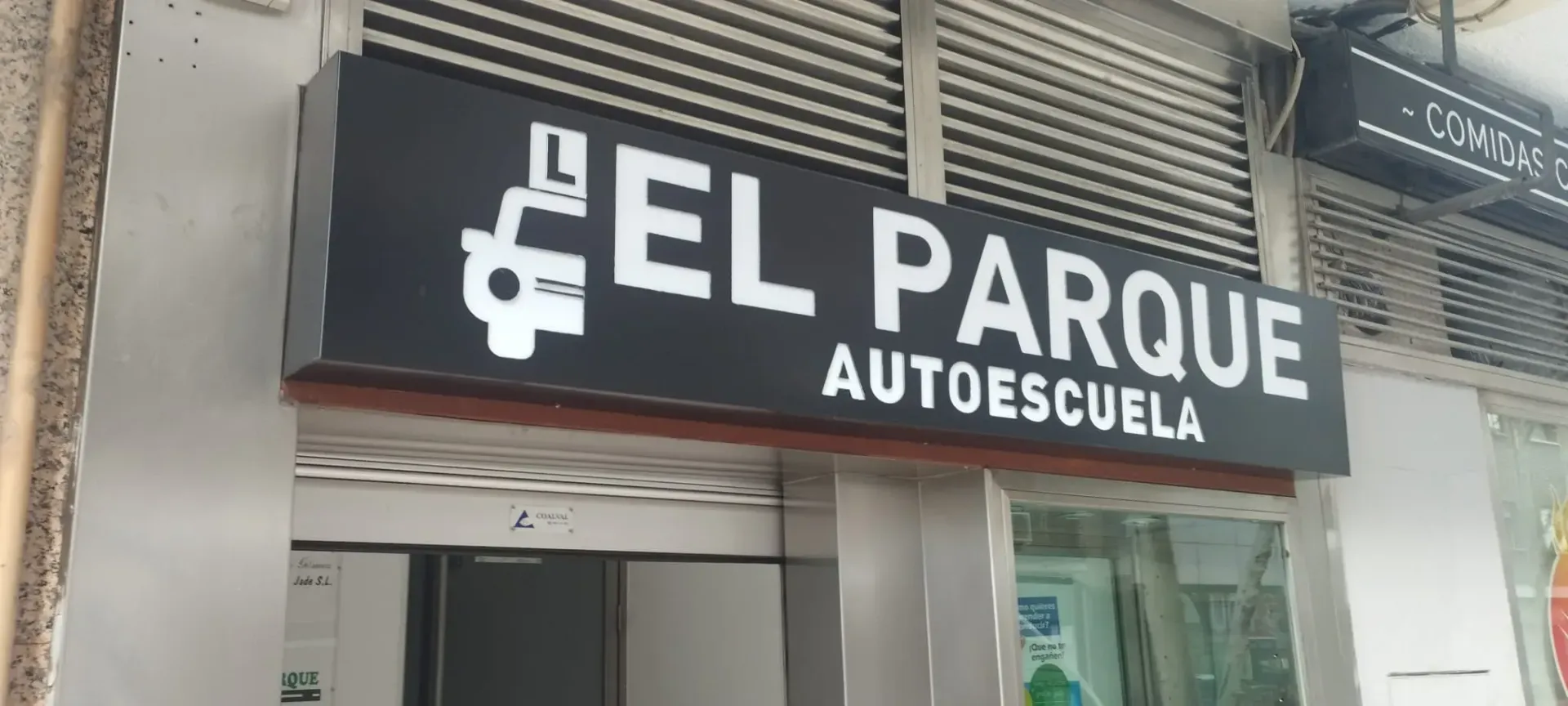 Un técnico con casco azul y chaleco reflectante habla por teléfono mientras trabaja en un ordenador portátil en un parque eólico.