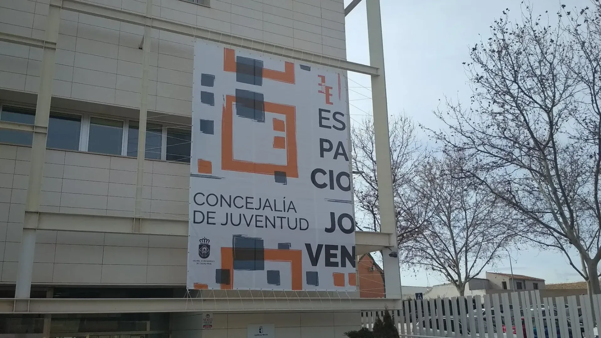 Un técnico con casco azul y chaleco reflectante habla por teléfono mientras trabaja en un ordenador portátil en un parque eólico.