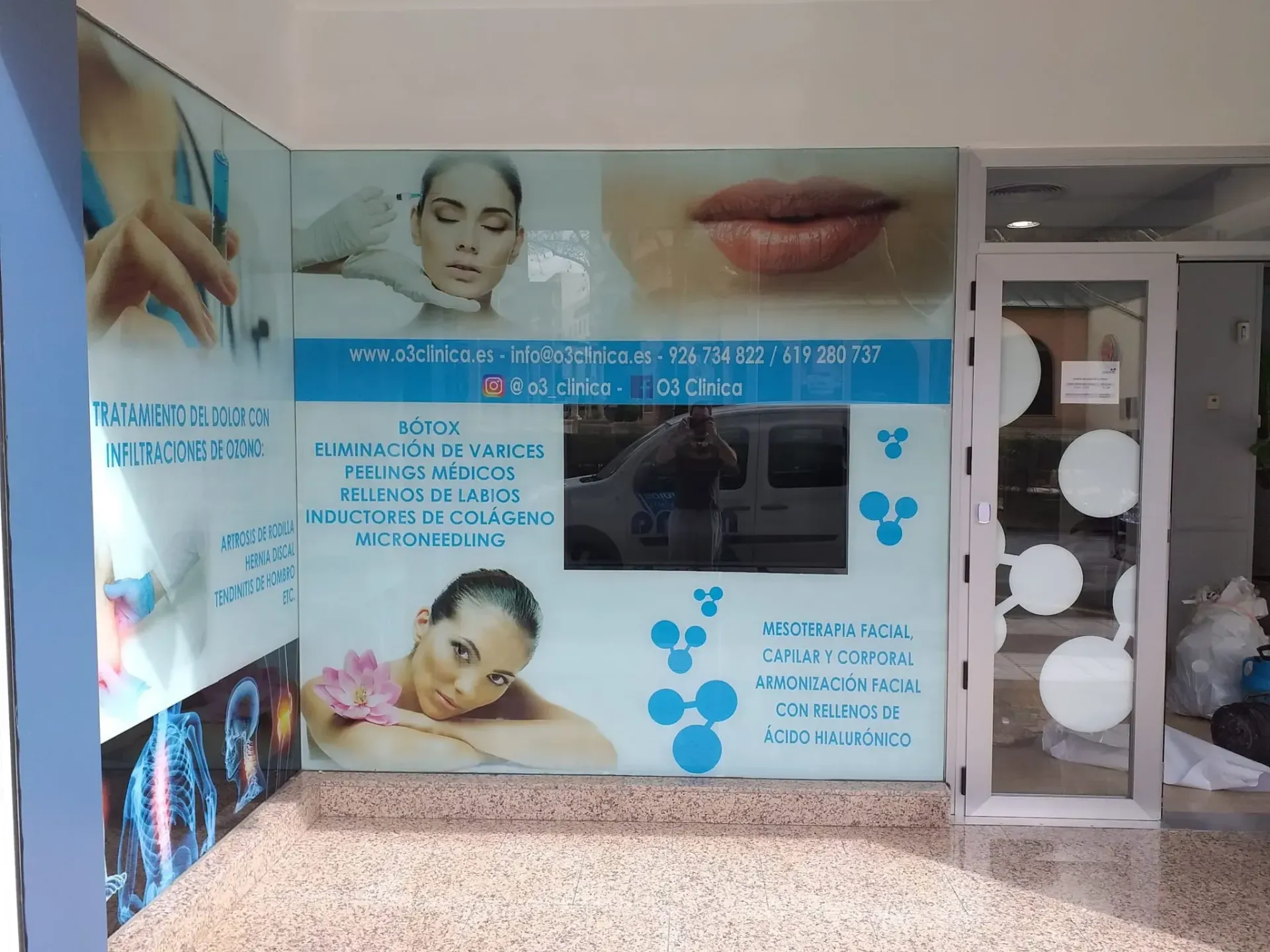 Un técnico con casco azul y chaleco reflectante habla por teléfono mientras trabaja en un ordenador portátil en un parque eólico.