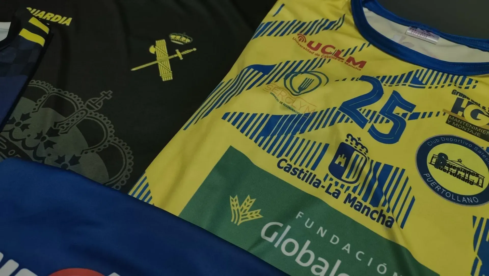 Un técnico con casco azul y chaleco reflectante habla por teléfono mientras trabaja en un ordenador portátil en un parque eólico.