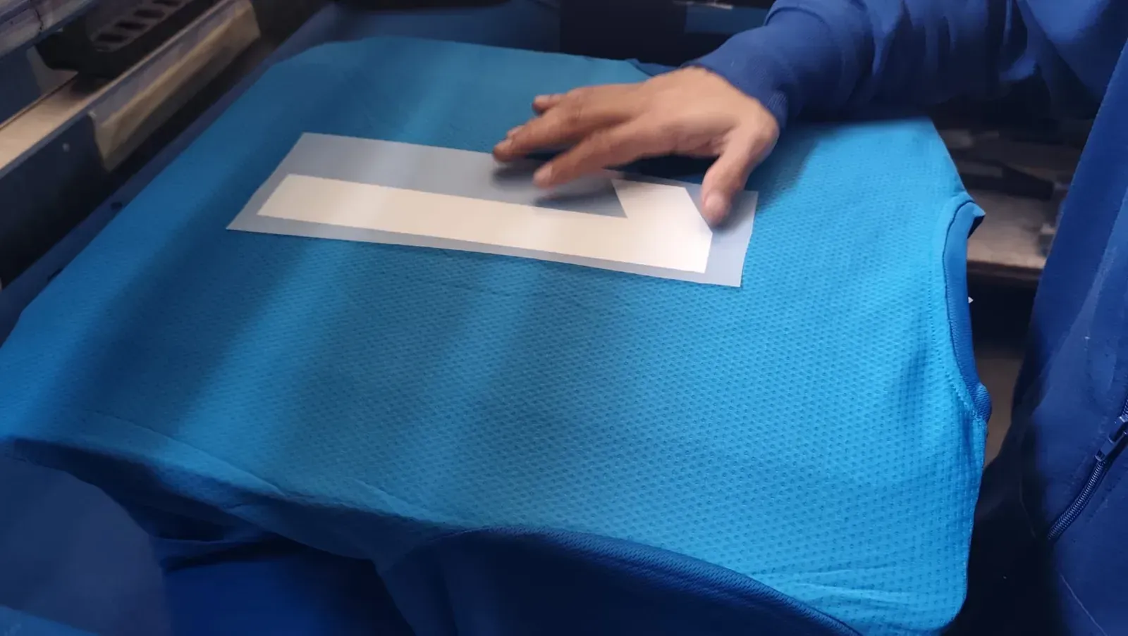 Un técnico con casco azul y chaleco reflectante habla por teléfono mientras trabaja en un ordenador portátil en un parque eólico.