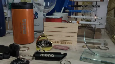 Escritorio desordenado con libros, relojes, cables, una esfera de cristal y una botella de agua naranja.