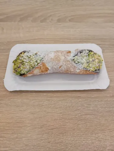 Tiramisú servido en un bol transparente, espolvoreado con cacao en polvo, sobre la mesa de una cafetería.