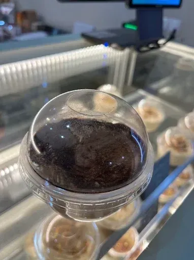 Trufa de chocolate negro en una vitrina transparente sobre el mostrador de una pastelería.