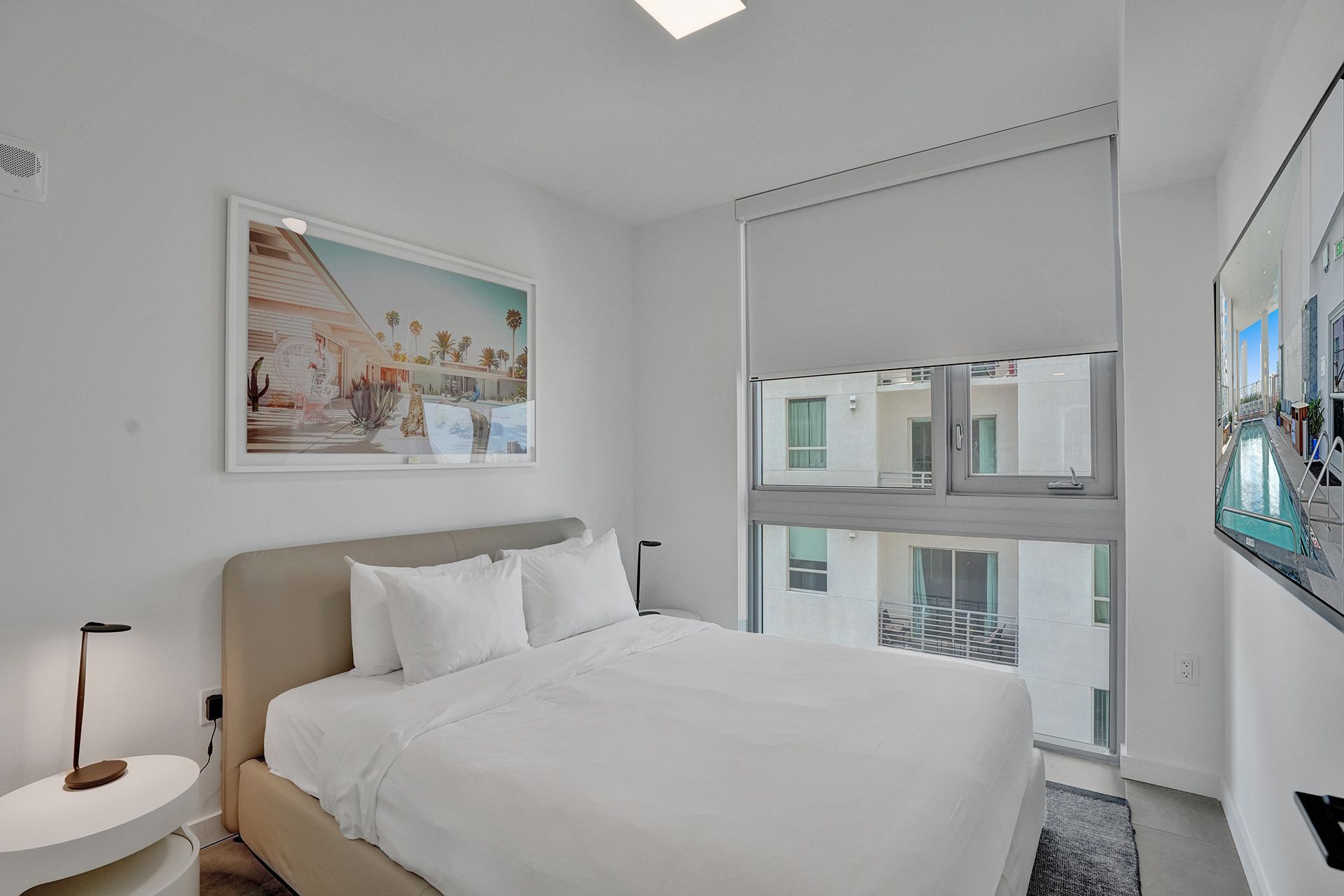 A bedroom with a large bed and a television on the wall.