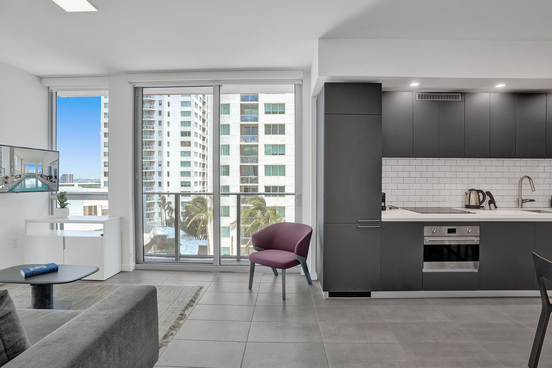 A living room with a couch and a chair and a kitchen