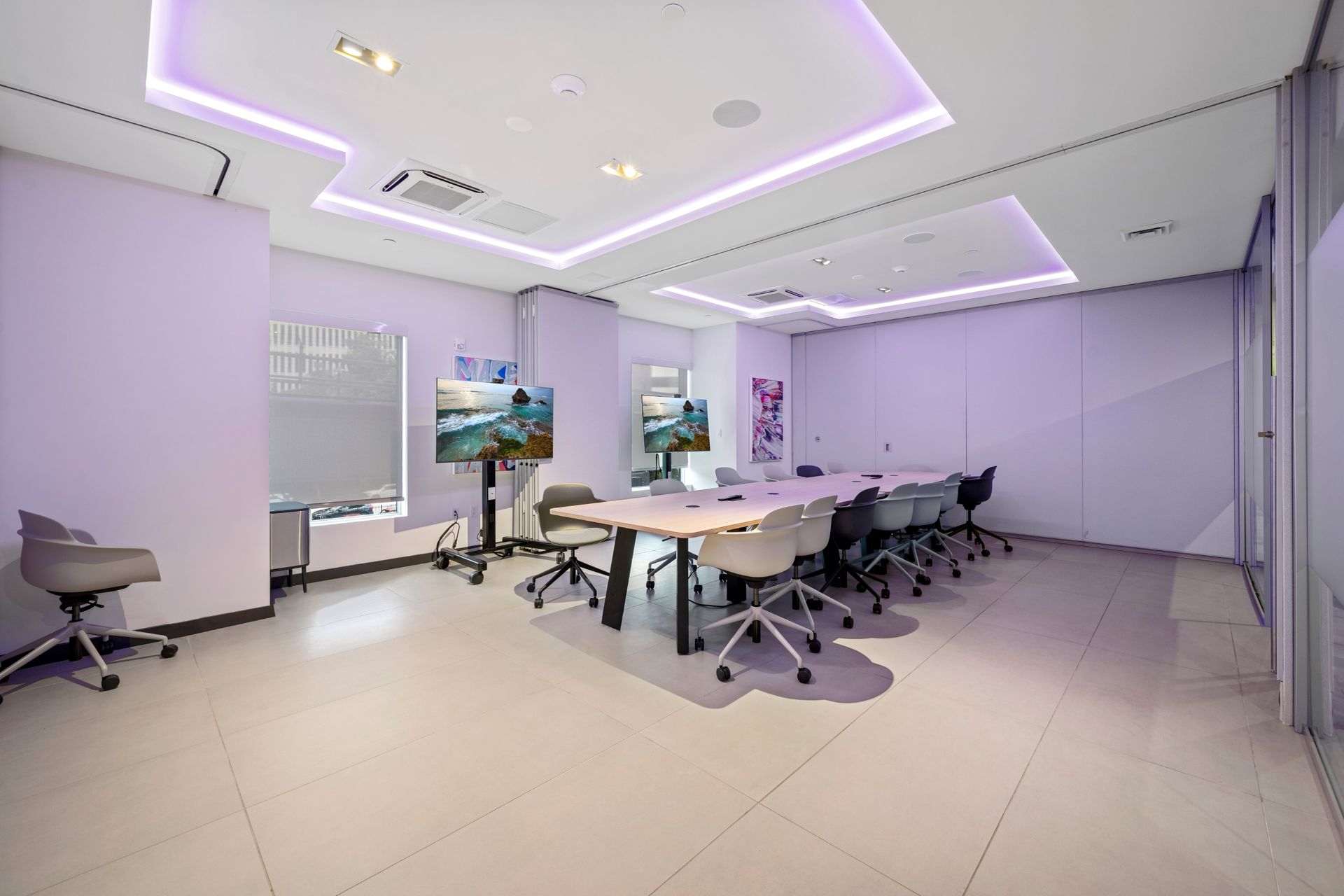 A conference room with a long table and chairs and a purple ceiling.