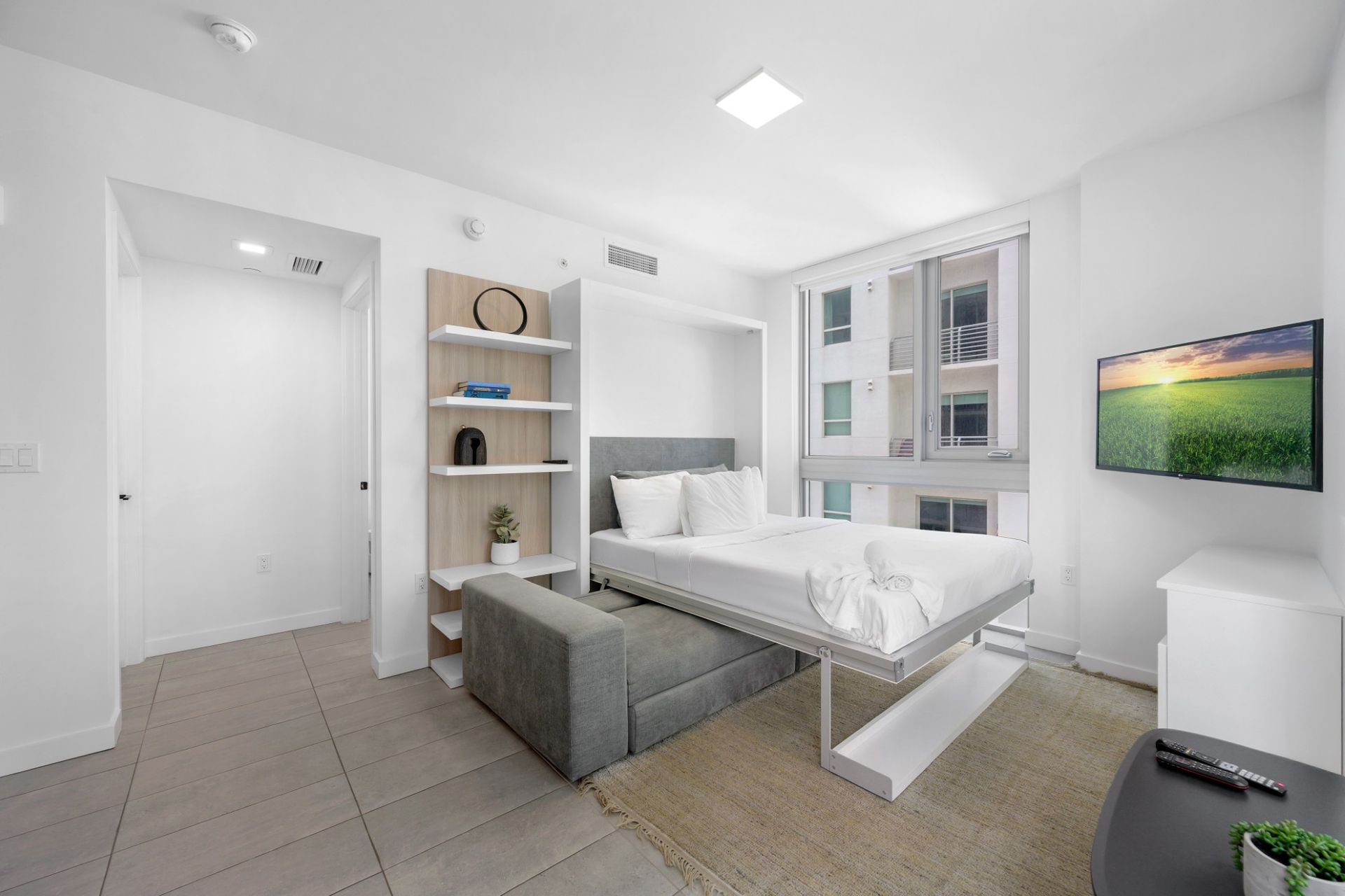A bedroom with a bed and a television on the wall.