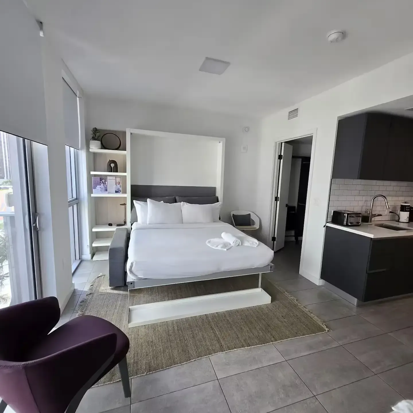 A bedroom with a large bed and a purple chair