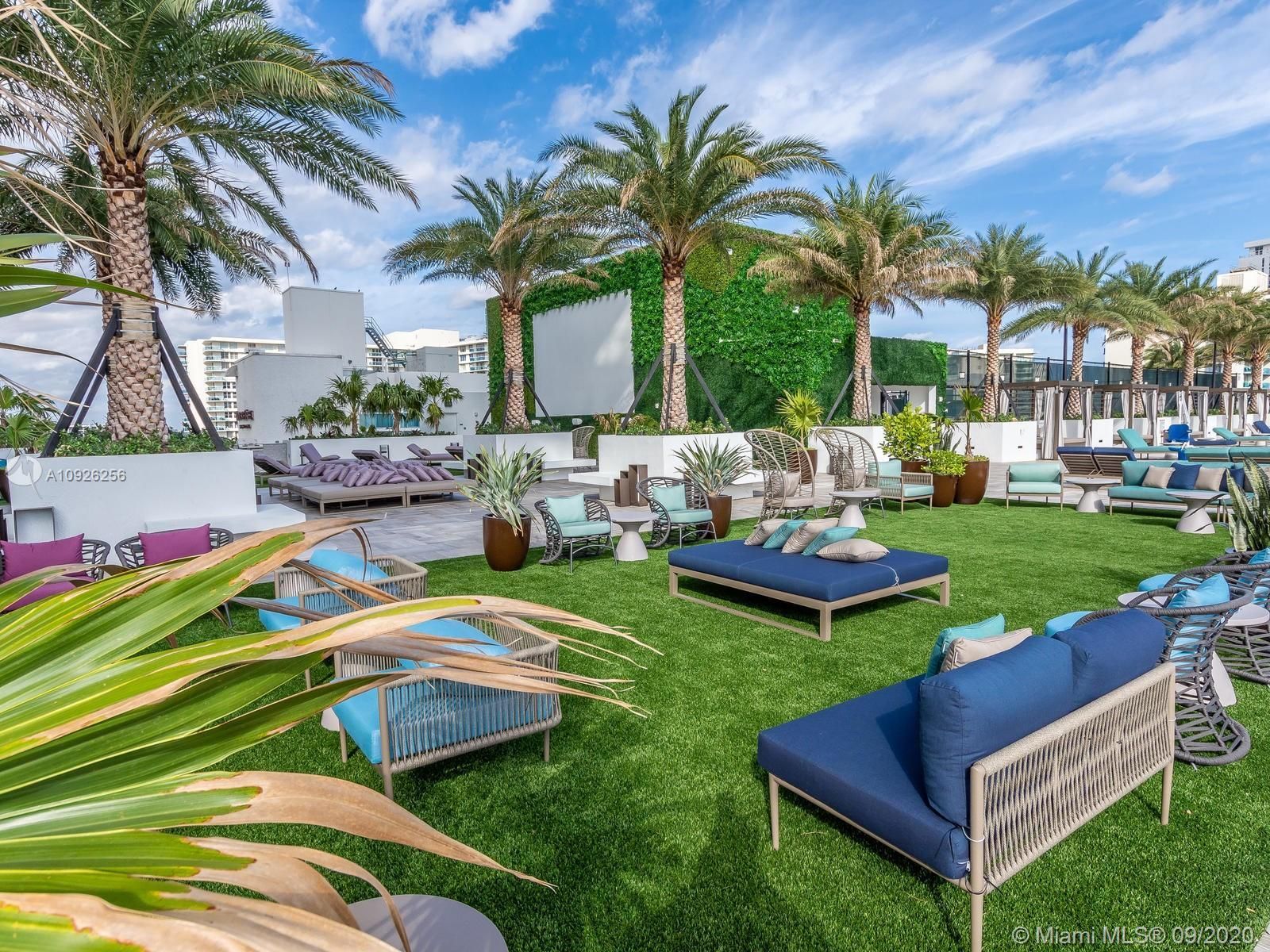 A large lawn filled with lots of furniture and palm trees.