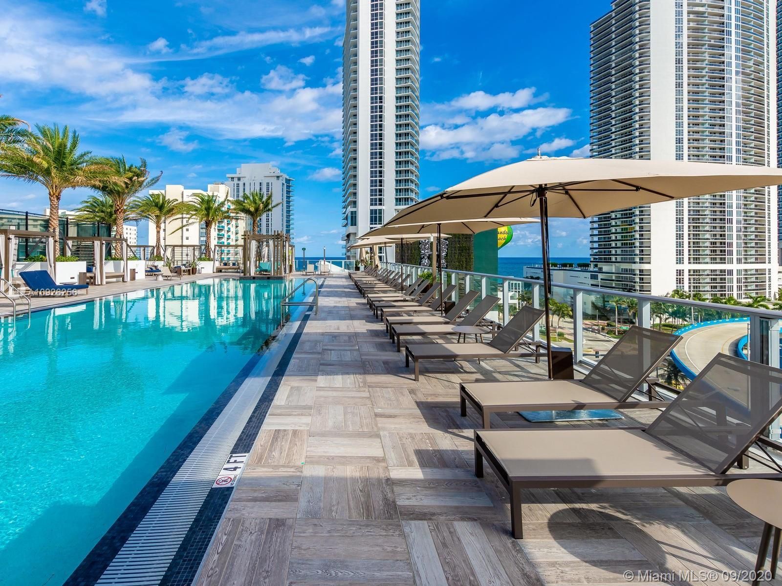 A large swimming pool surrounded by lounge chairs and umbrellas.