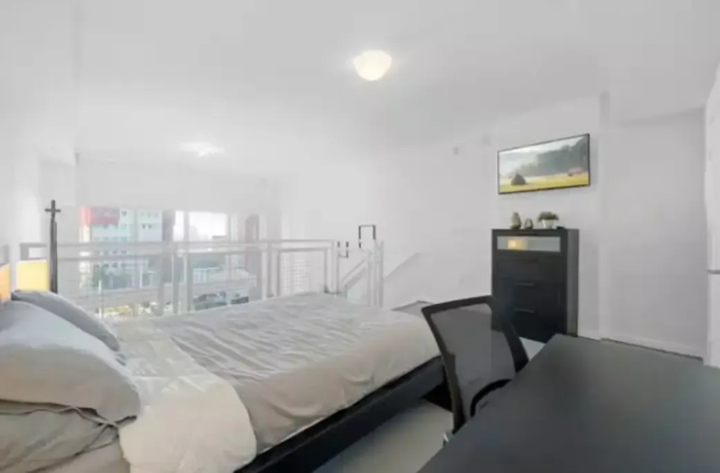 A bedroom with a bed , table , chairs and a picture on the wall.
