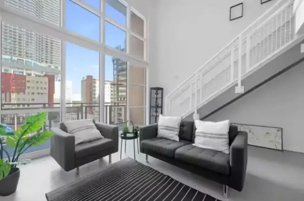 A living room with a couch , chairs , and stairs.