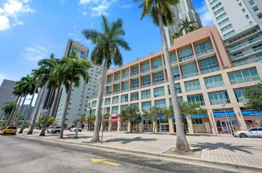 A row of tall buildings with palm trees in front of them in a city.