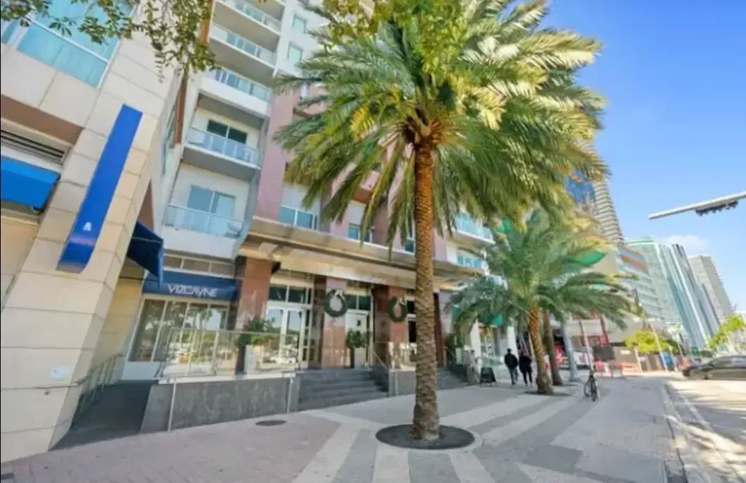 A building with a lot of windows and palm trees in front of it.