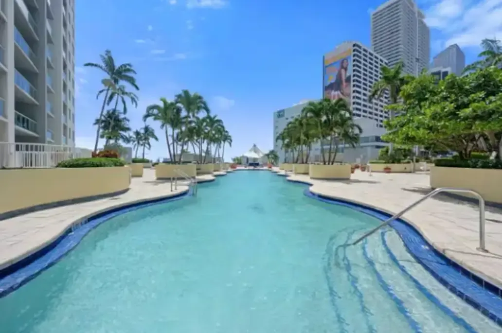 A large swimming pool surrounded by palm trees and buildings