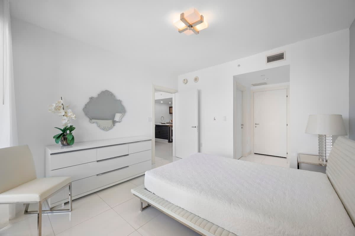 A bedroom with a bed , dresser , chair and mirror