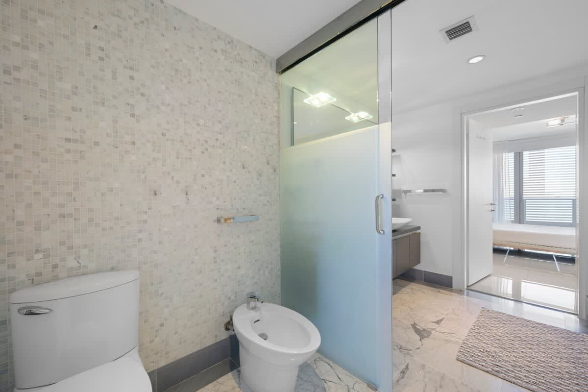A bathroom with a toilet , bidet and shower.