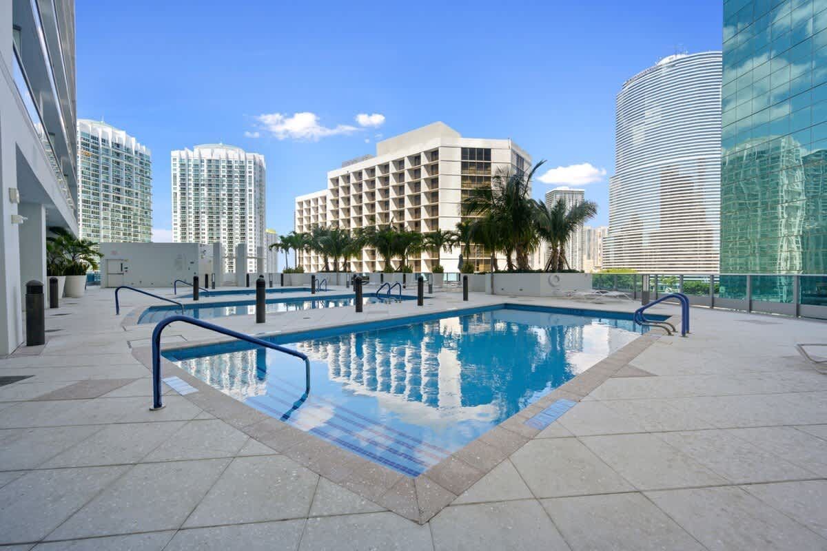 A large swimming pool in the middle of a city with buildings in the background.