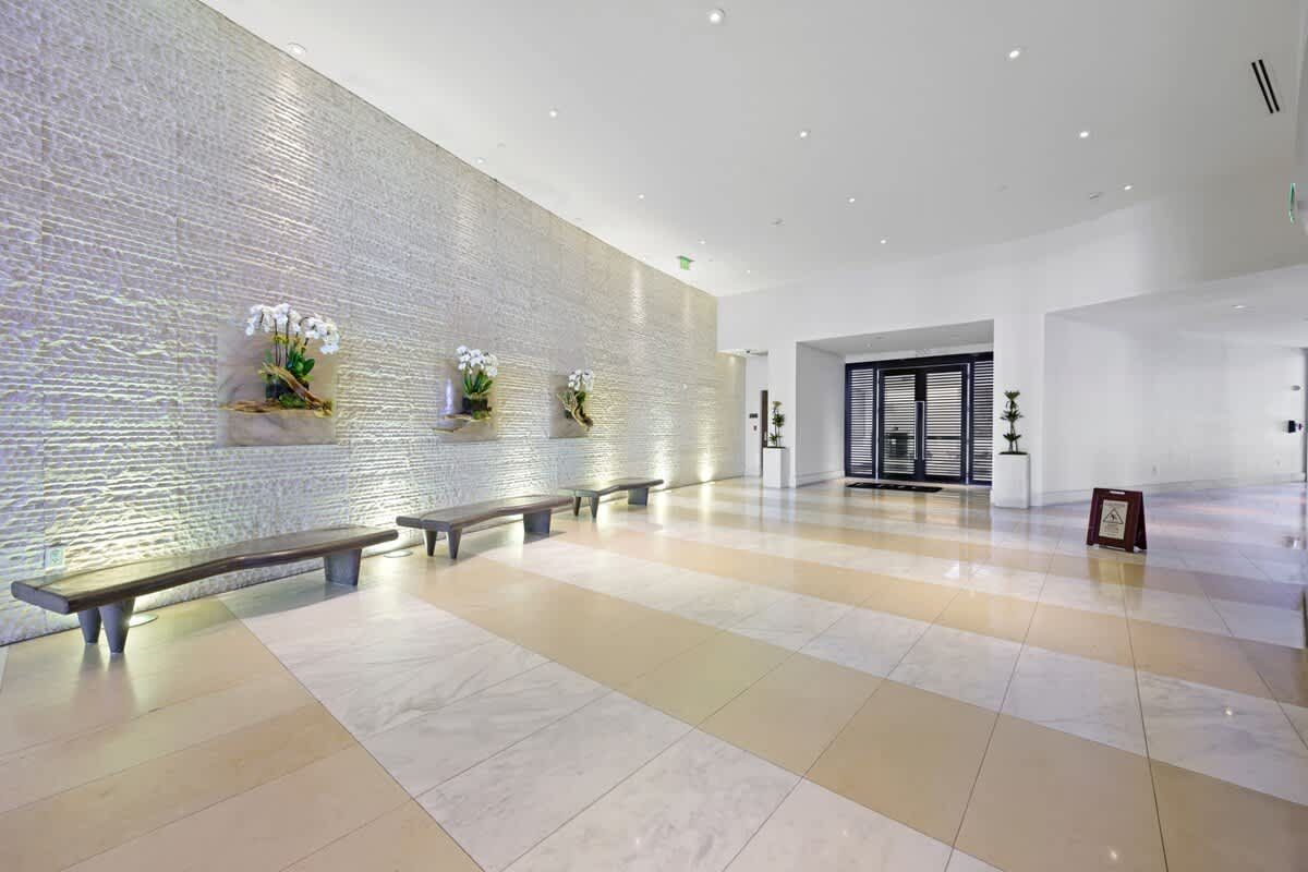 A large lobby with a row of benches in front of a white wall.