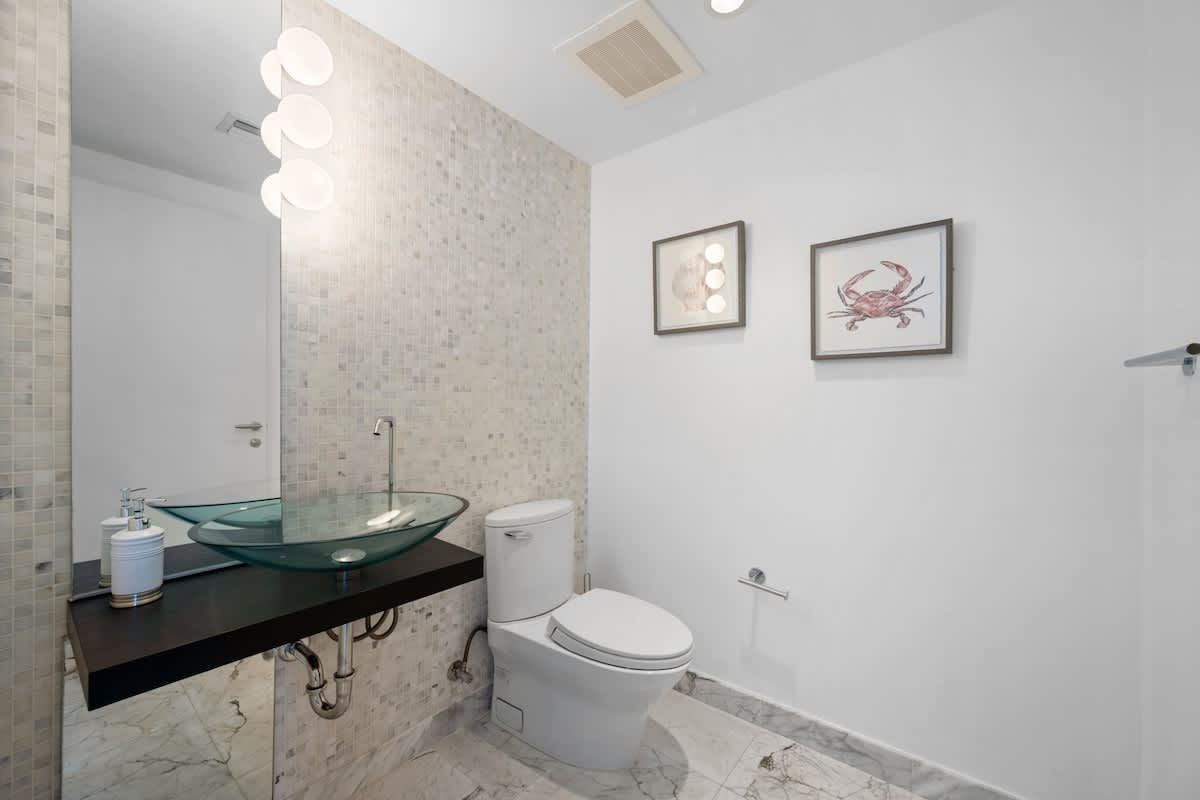 A bathroom with a toilet , sink and mirror.