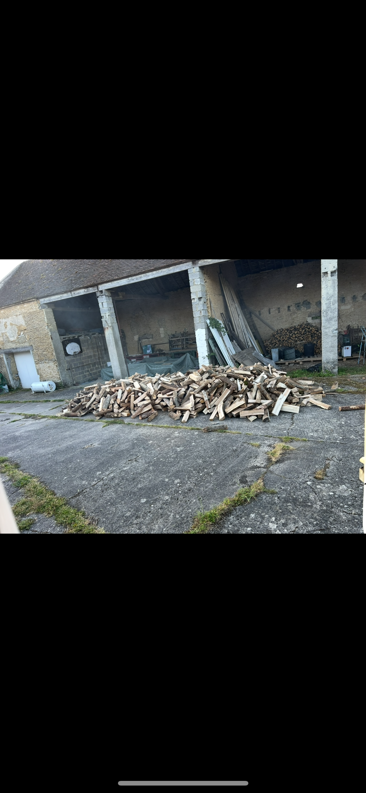 Un homme en pull, ajoute un morceau de bois à une cheminée en briques allumée.