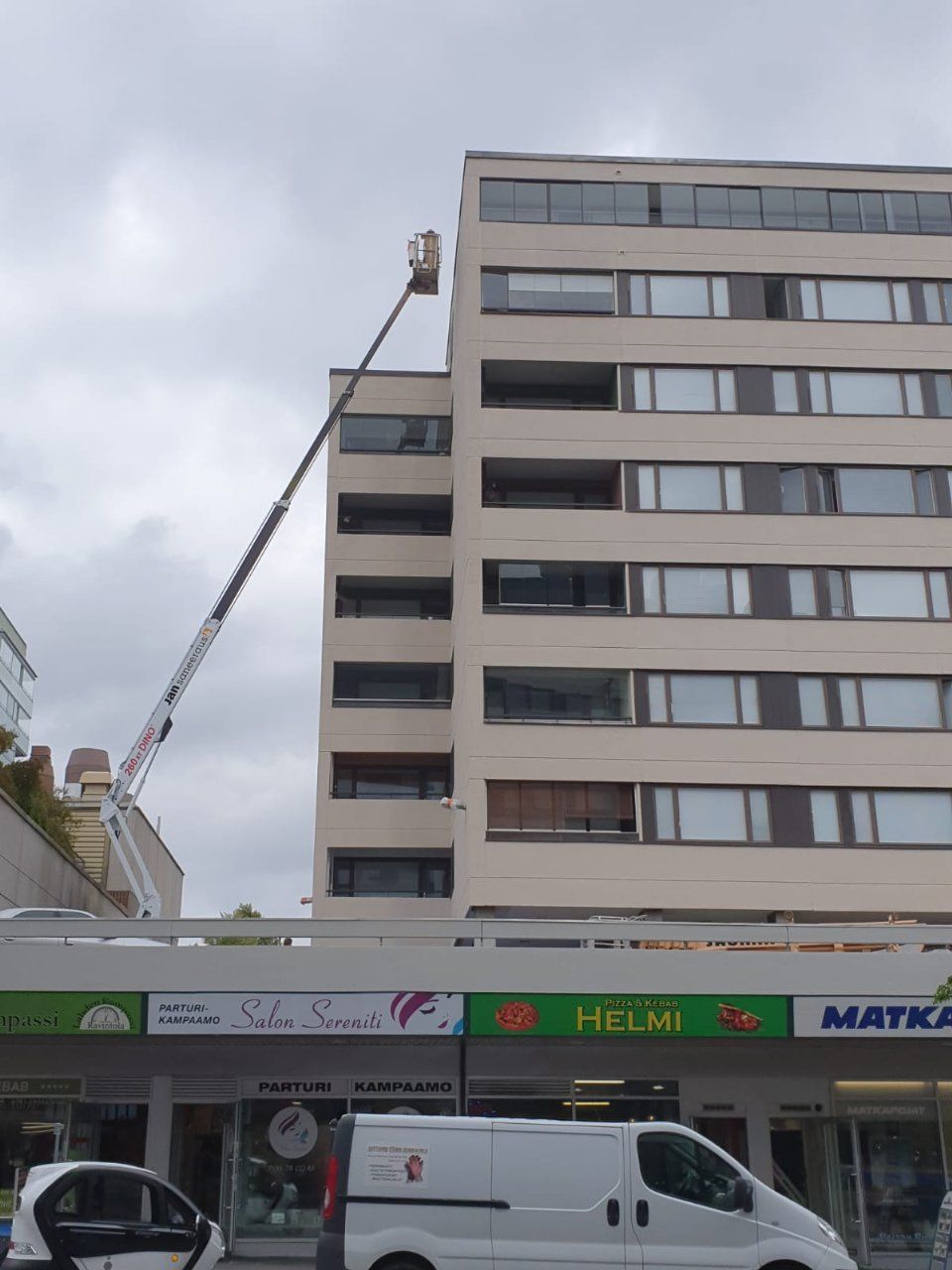 Korkea hissi saavuttaa rakennuksen ylemmät kerrokset. Valkoinen pakettiauto on pysäköitynä alapuolelle.