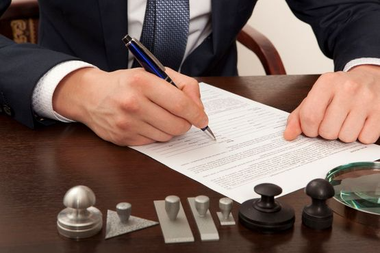 Un hombre con traje y corbata está firmando un documento.
