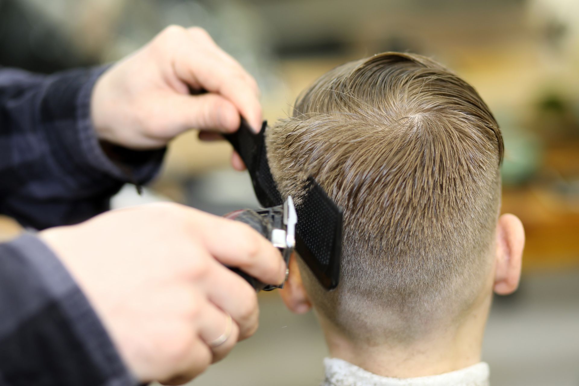 Ein Mann lässt sich von einem Friseur mit einer Haarschneidemaschine die Haare schneiden.