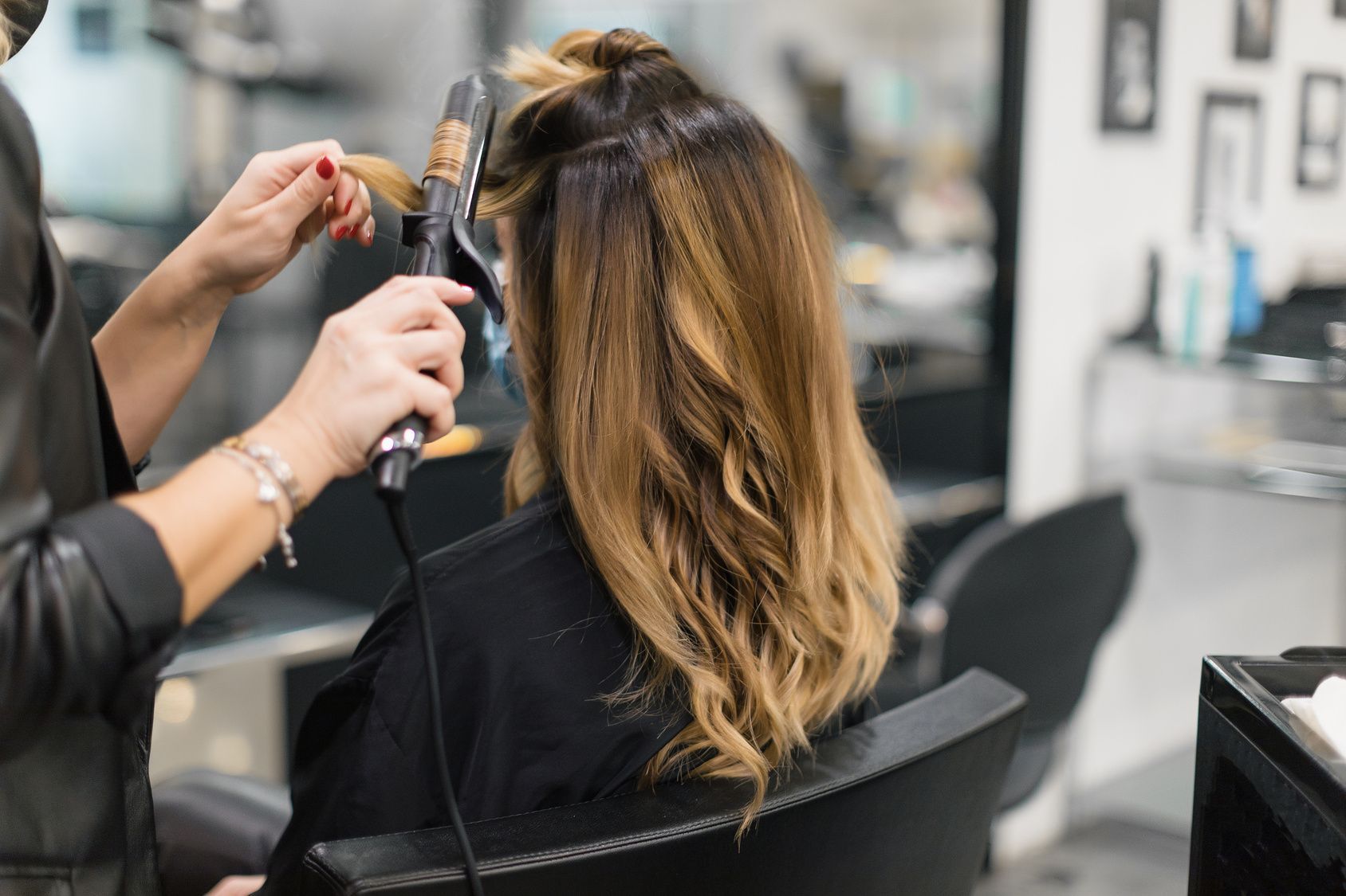 Eine Frau lässt sich in einem Salon von einem Friseur die Haare machen.
