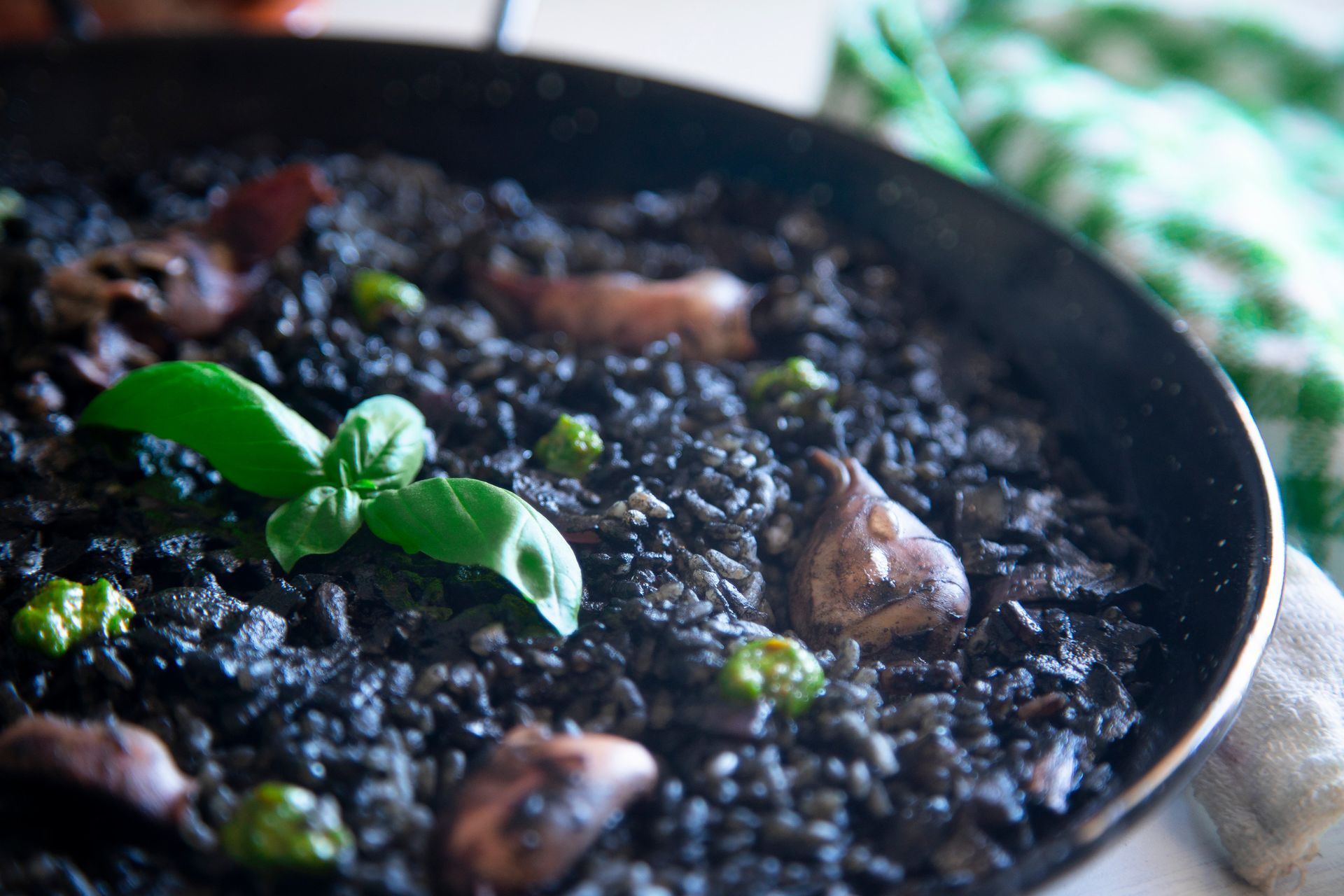 Una sartén llena de arroz negro y verduras sobre una mesa.