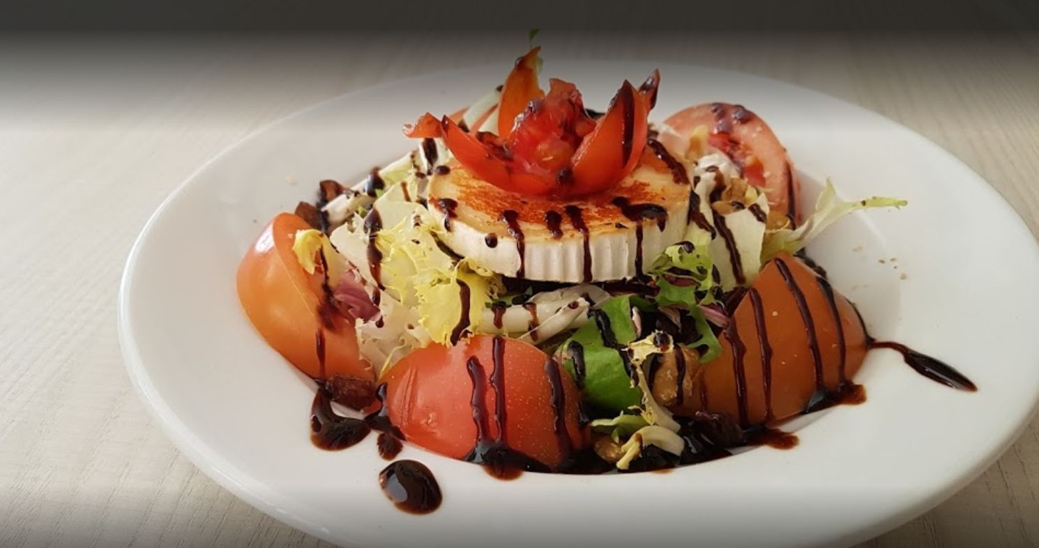 Un plato blanco cubierto con una ensalada de tomates y lechuga.