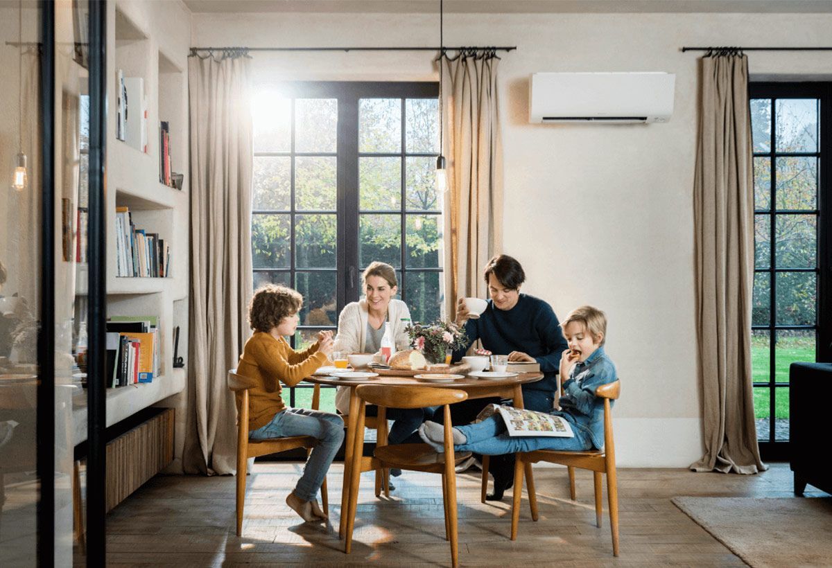 Famille autour d'une table de cuisine en dessous d'une d'une climatisation