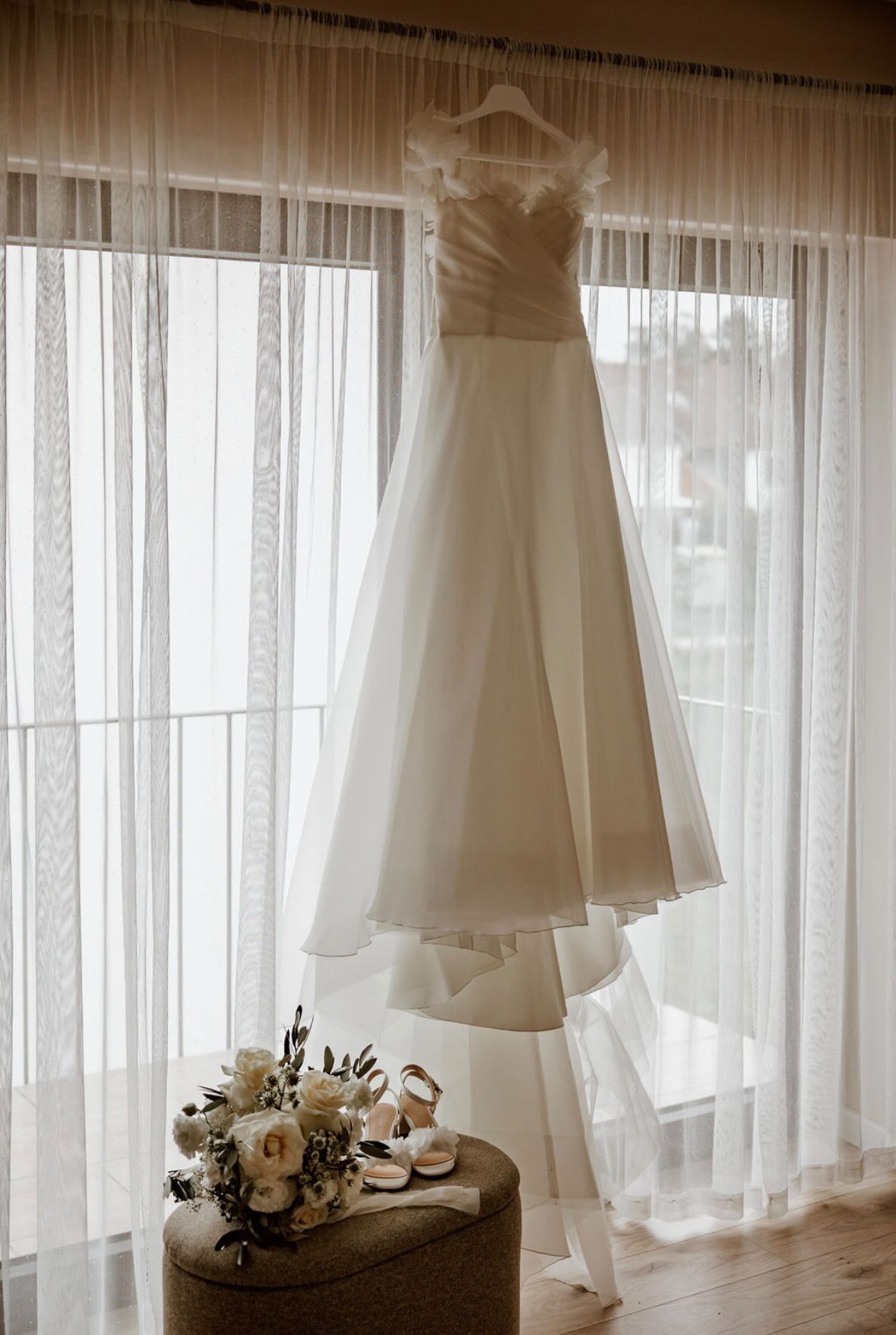 Brautkleid am Fenster als Vorbereitung der Hochzeit mit eleganter Hochzeitsdekoration