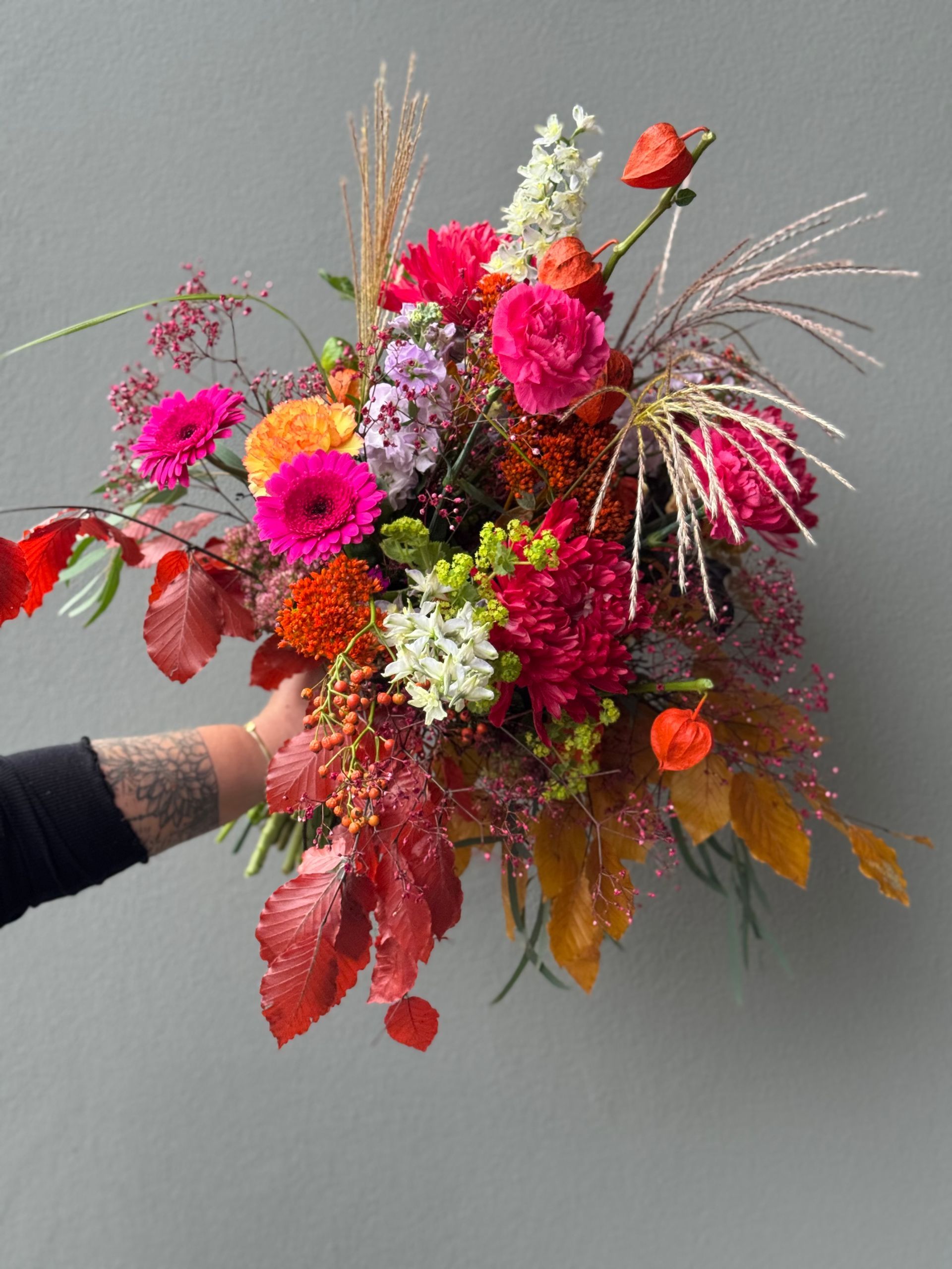 Farbenfroher Blumenstrauß mit Gerbera, Rosen und Gräsern, lebendig gestaltet