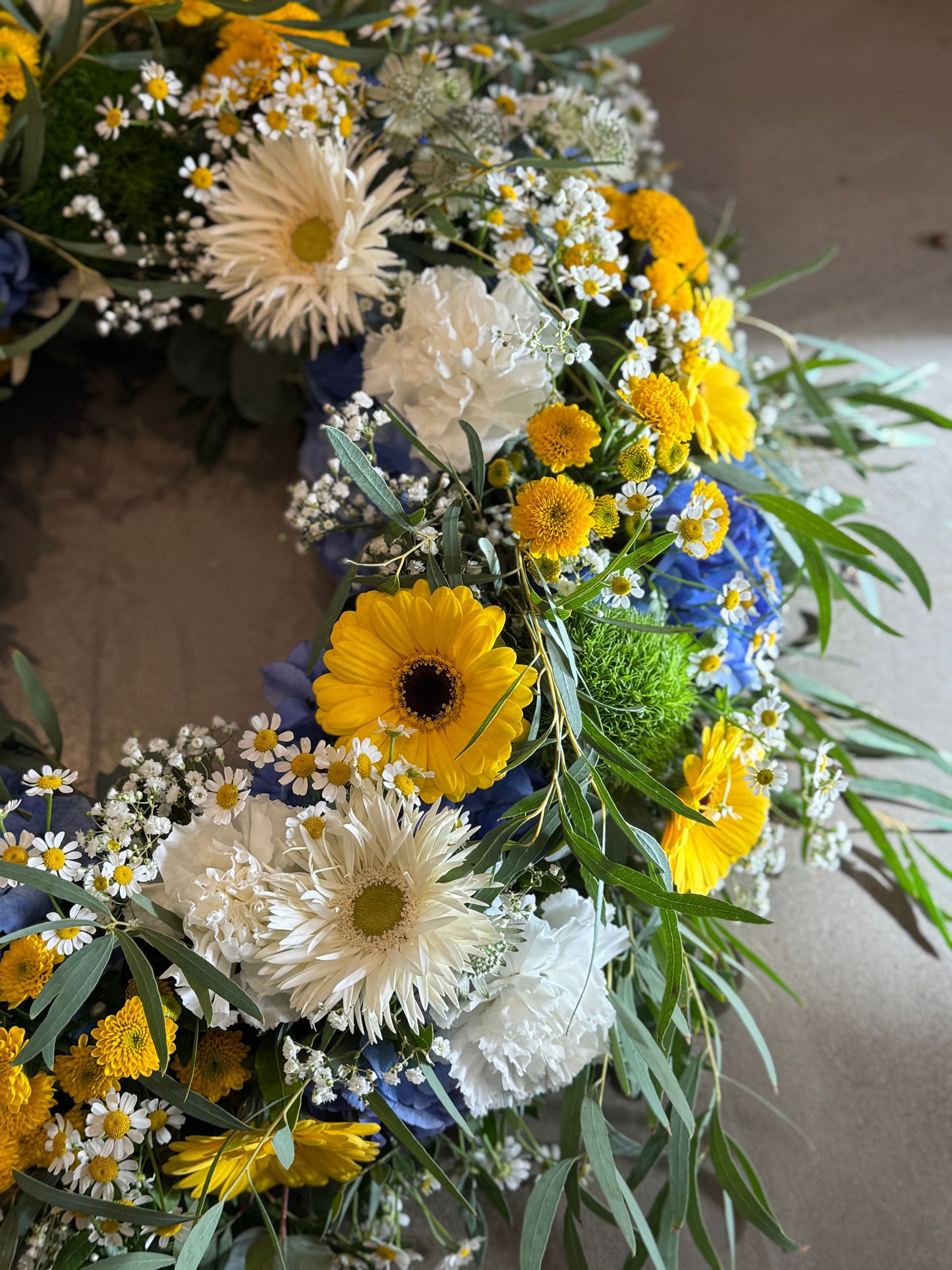 Trauerkranz mit weißen und gelben Blumen, frisch und natürlich gestaltet