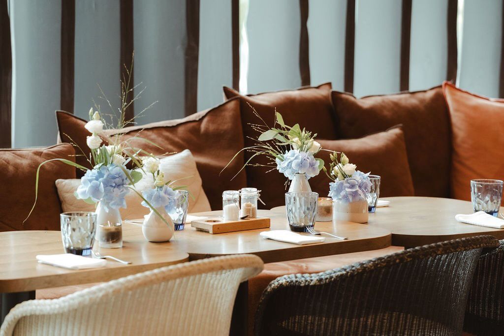 Tischdeko mit kleinen Blumenvasen und Kerzen, elegante Eventgestaltung
