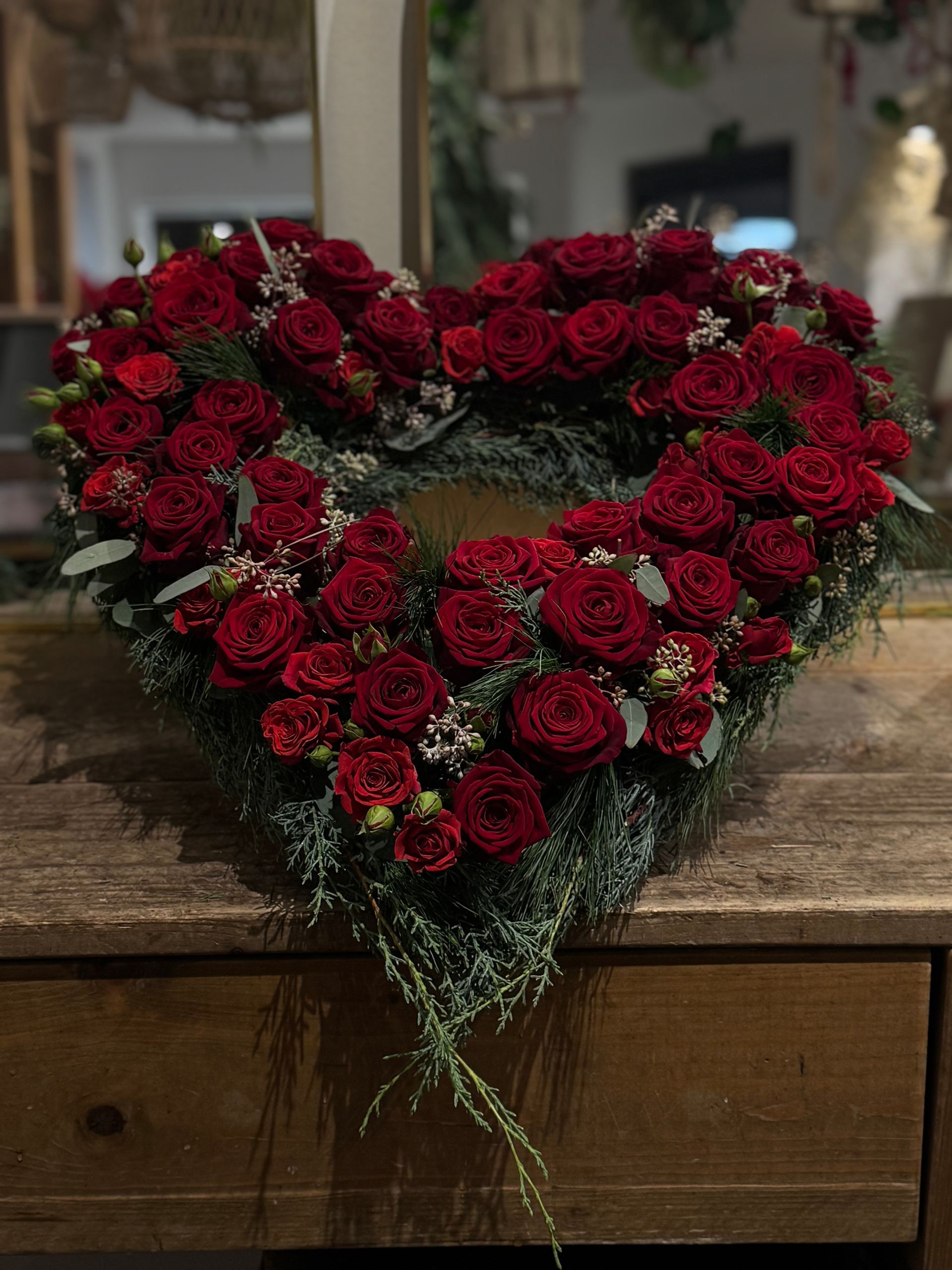 Kranz aus roten Rosen, in Herzform gesteckt, traditioneller Blumenschmuck