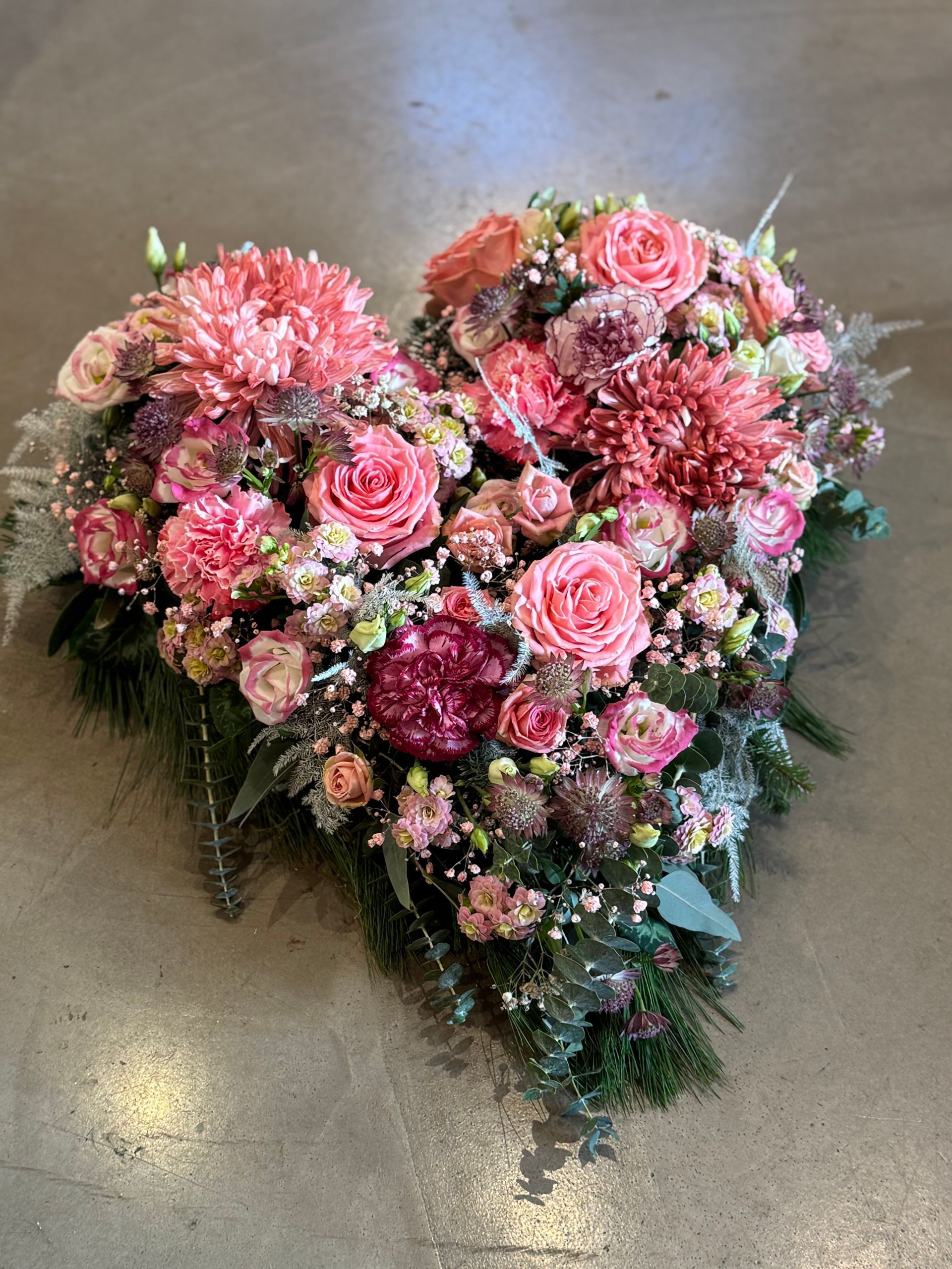 Trauerkranz in Rosa mit Rosen und Chrysanthemen, in Herzform gebunden