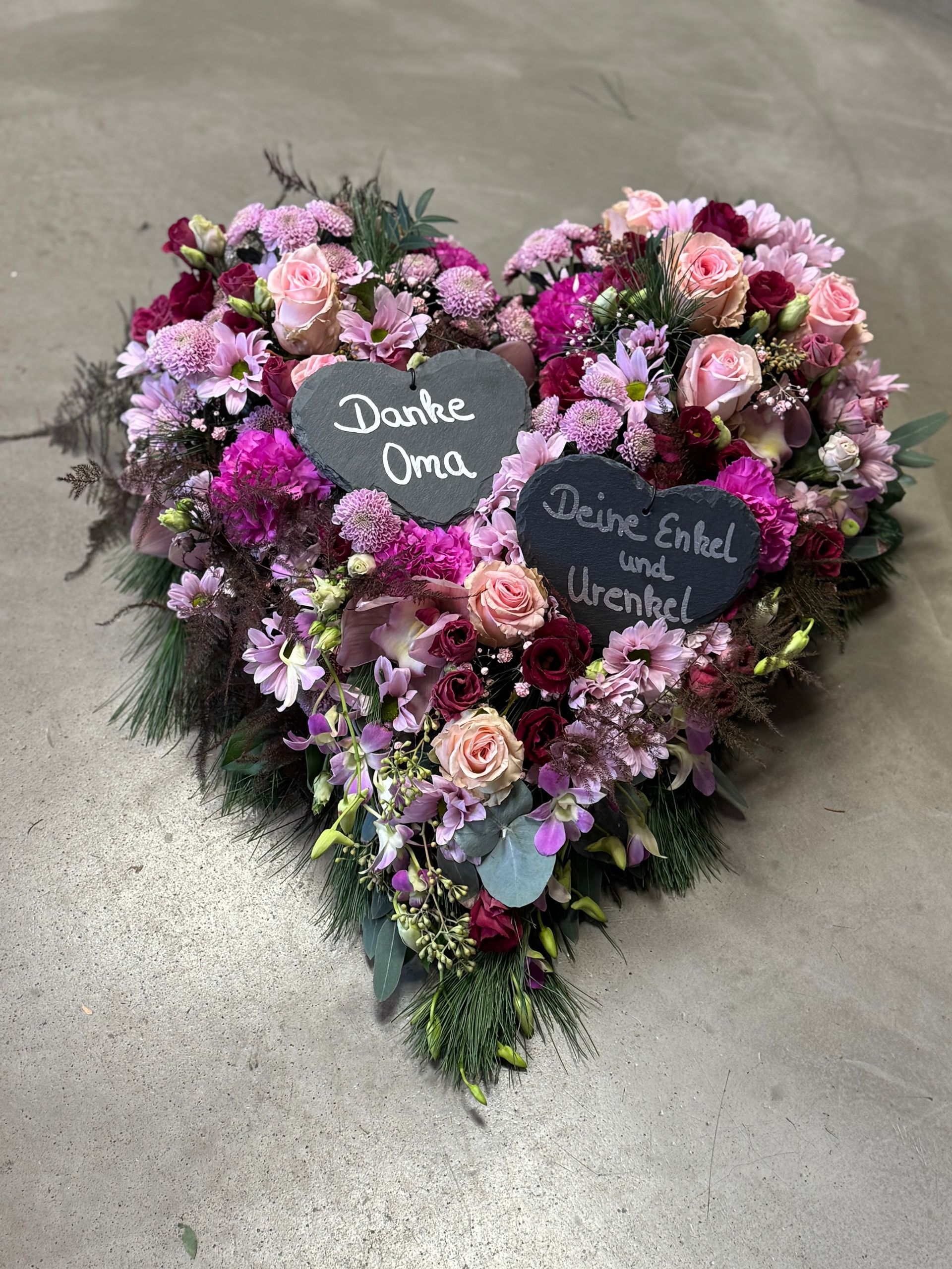 Herzkranz mit rosa und lila Blüten und Beschriftung, persönlicher Abschiedsgruß