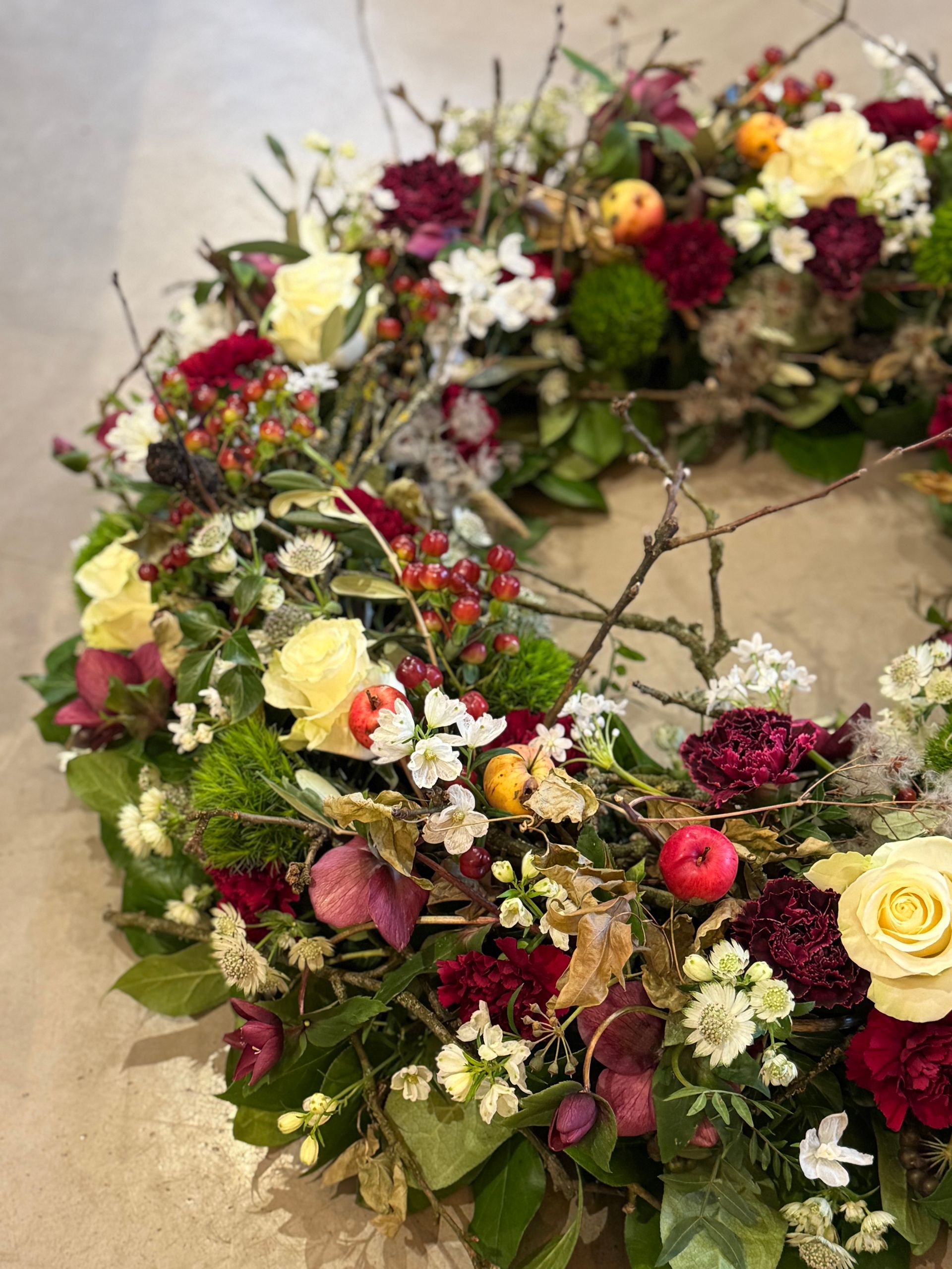 Bunter Trauerkranz mit Rosen und saisonalen Blumen, natürlich arrangiert