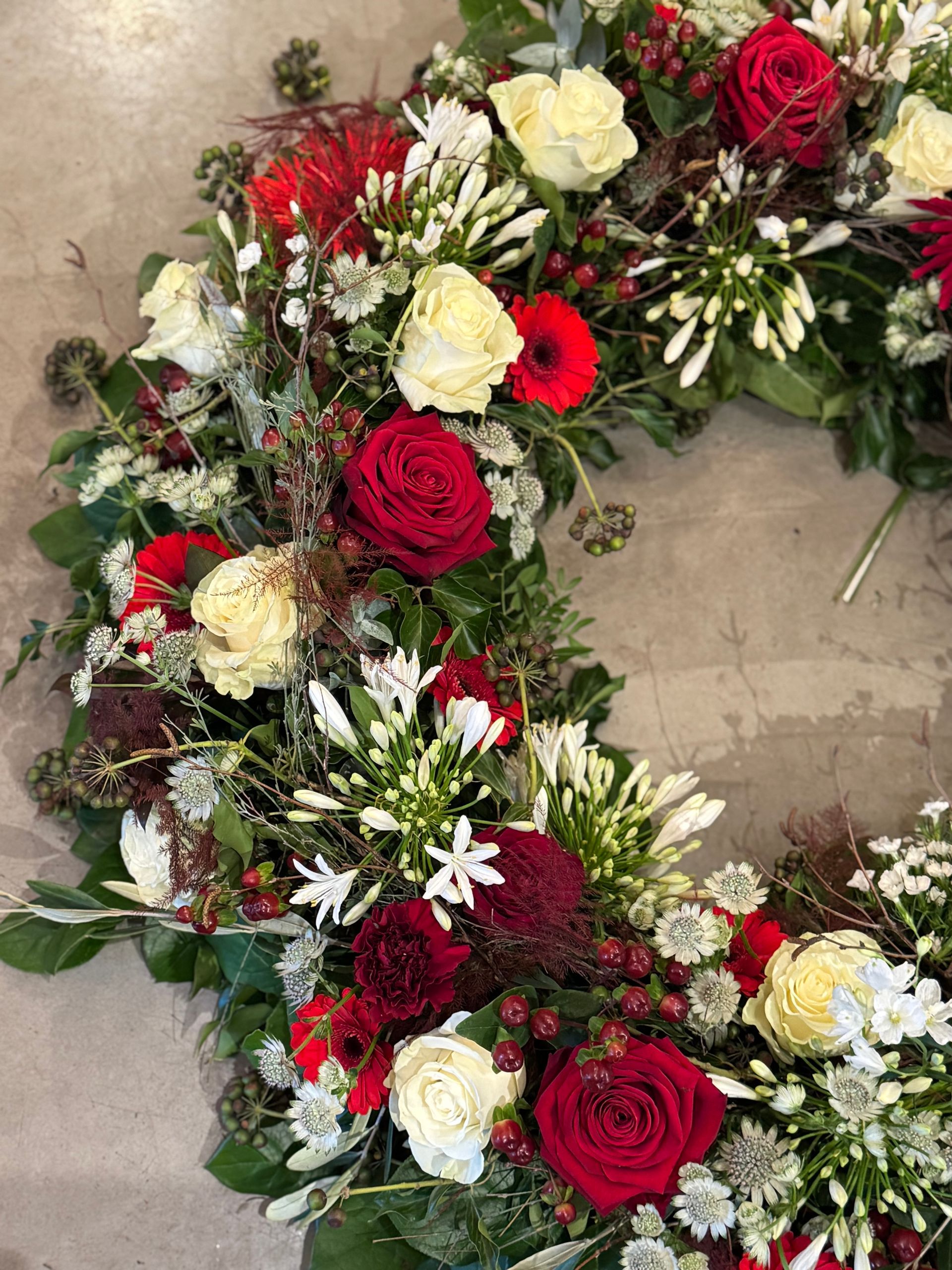 Trauerkranz mit roten und weißen Rosen, klassisch und elegant gestaltet