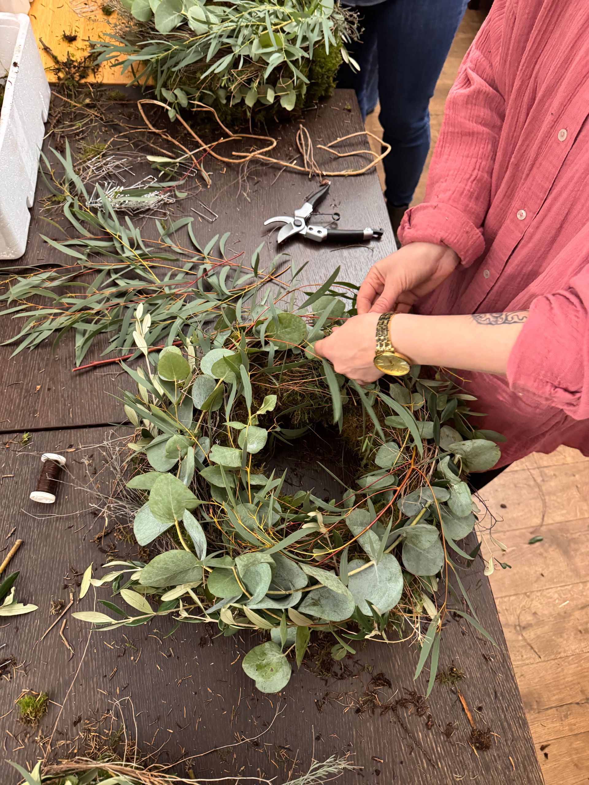 Workshop-Teilnmehmerin bindet Blumenstrauß mit Eukalyptus und Werkzeug im Blumengeschäft Blütensturm in Merzig