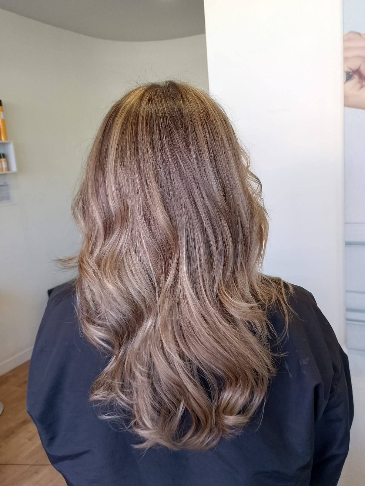 Una mujer con cabello largo y castaño está sentada en una silla.