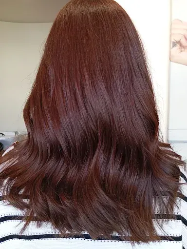 Una mujer se está cortando el pelo con unas tijeras por un peluquero.