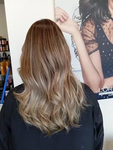 Una mujer se está tiñendo el pelo en una peluquería.